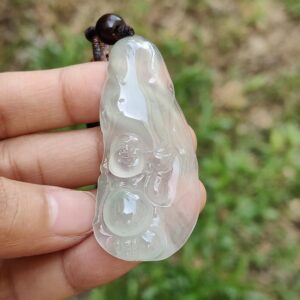 eine Hand, die einen Jadeanhänger hält
