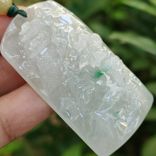 a hand holding a white and green necklace