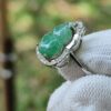 a hand wearing a white glove with a green stone ring