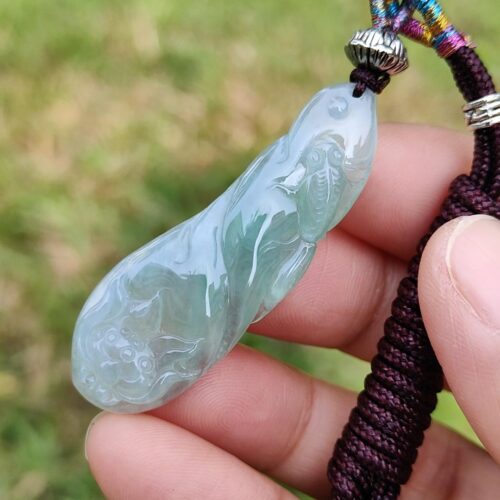 a hand holding a jade pendant