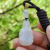 Una mano sosteniendo un colgante de jade blanco.