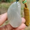 a hand holding a jade pendant