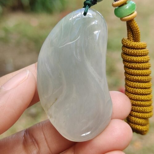 a hand holding a jade pendant