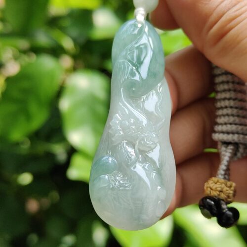 a hand holding a jade pendant
