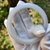 a gloved hand holding a white ring