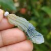 a hand holding a jade leaf pendant