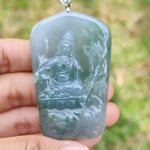 a hand holding a jade pendant