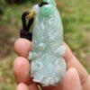 a hand holding a jade pendant