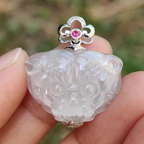 a hand holding a white jade pendant