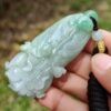 a hand holding a jade pendant