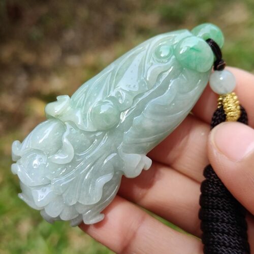 a hand holding a jade pendant