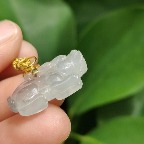 a hand holding a small white animal pendant