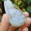 a hand holding a jade pendant