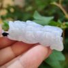एक हाथ में जेड पेंडेंट थामे हुए