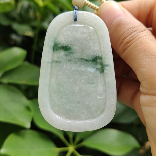 a hand holding a jade pendant