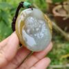 a hand holding a jade pendant
