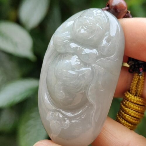 a hand holding a jade pendant