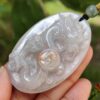 a hand holding a jade pendant