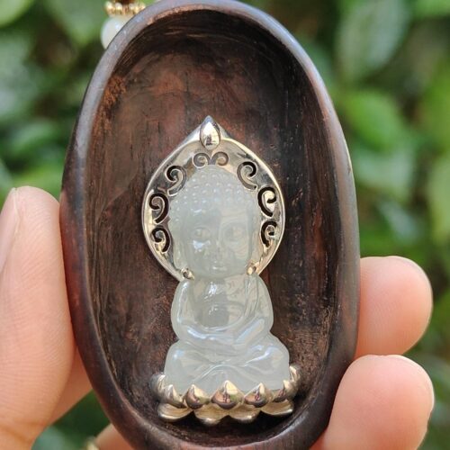 a hand holding a carved wooden object with a small white buddha statue