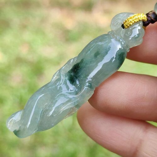 a hand holding a jade pendant