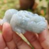 a hand holding a small jade frog