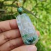 a hand holding a jade pendant