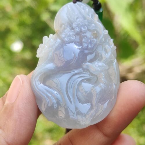 a hand holding a jade pendant
