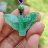 eb4fb0f83d9e62411da7b9a872d239d8 a hand holding a green stone pendant
