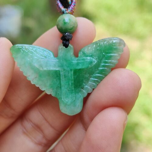 a hand holding a green stone pendant