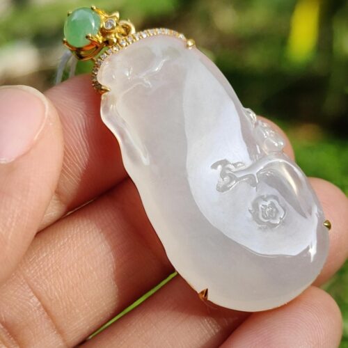 a hand holding a jade pendant