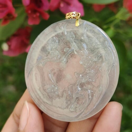 a hand holding a round white object with a gold filigree design