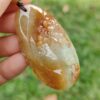 Una mano sosteniendo un colgante de piedra.