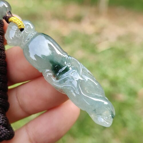 a hand holding a jade pendant
