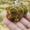 Una mano sosteniendo un pequeño animal de piedra verde.