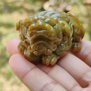 Una mano sosteniendo un pequeño animal de piedra verde.
