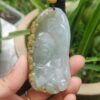a hand holding a jade pendant