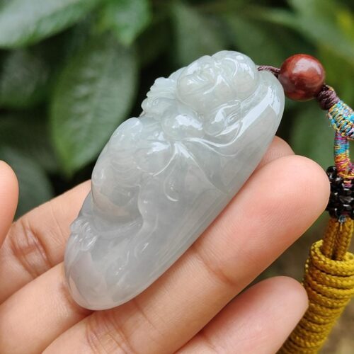 a hand holding a jade pendant