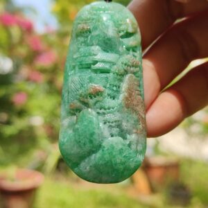 a hand holding a jade pendant