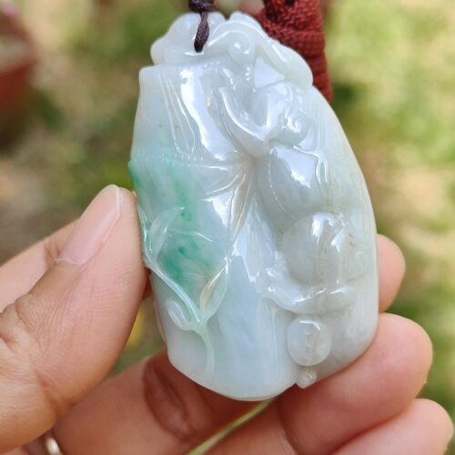 a hand holding a jade pendant