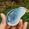 une main tenant un pendentif en jade