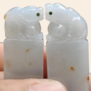 a hand holding a pair of white stone animals