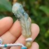 một bàn tay cầm một mặt dây chuyền ngọc bích