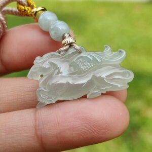 a hand holding a jade pendant