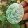 a hand holding a jade pendant