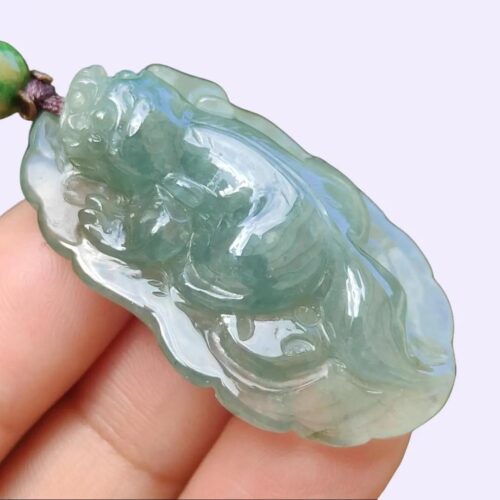 a hand holding a jade pendant