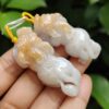 a hand holding a pair of white and orange carved elephants