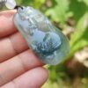 a hand holding a jade pendant
