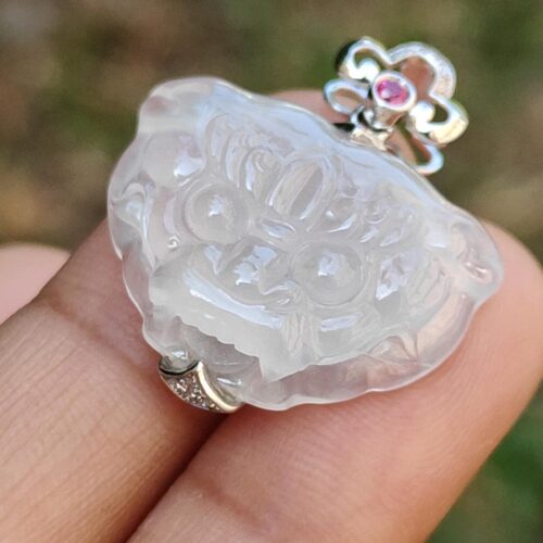 a hand holding a white jade pendant