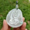 a hand holding a jade pendant