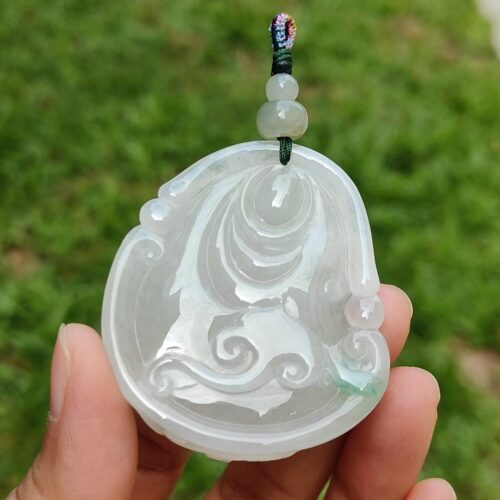 a hand holding a jade pendant